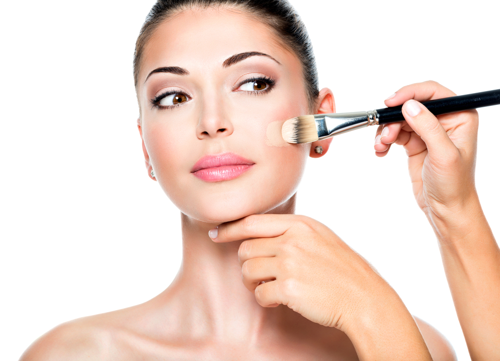 Maquiador aplicando em pele do rosto feminina a melhor base para pele oleosa